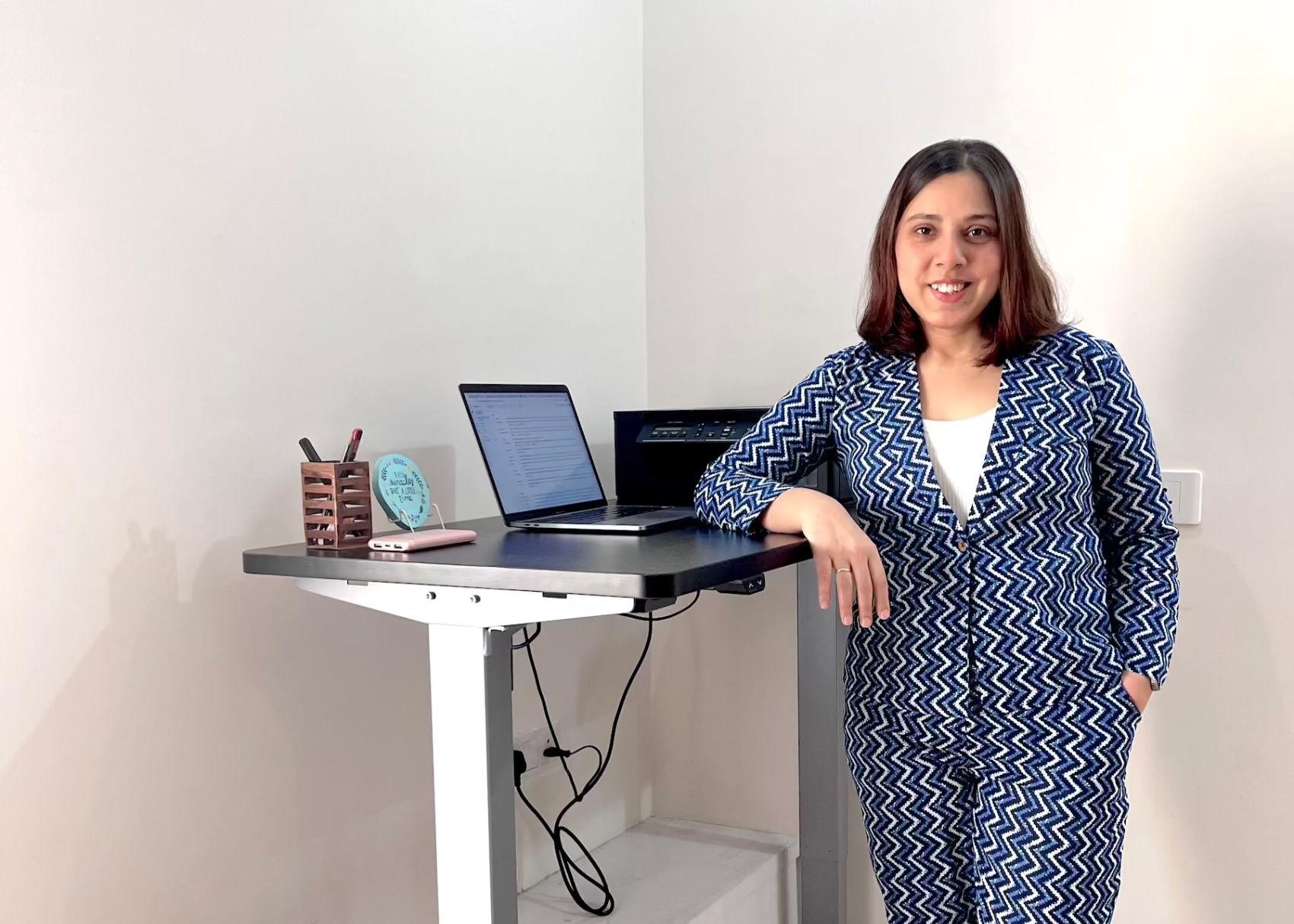 Founder standing next to a standing desk with a laptop and office supplies.